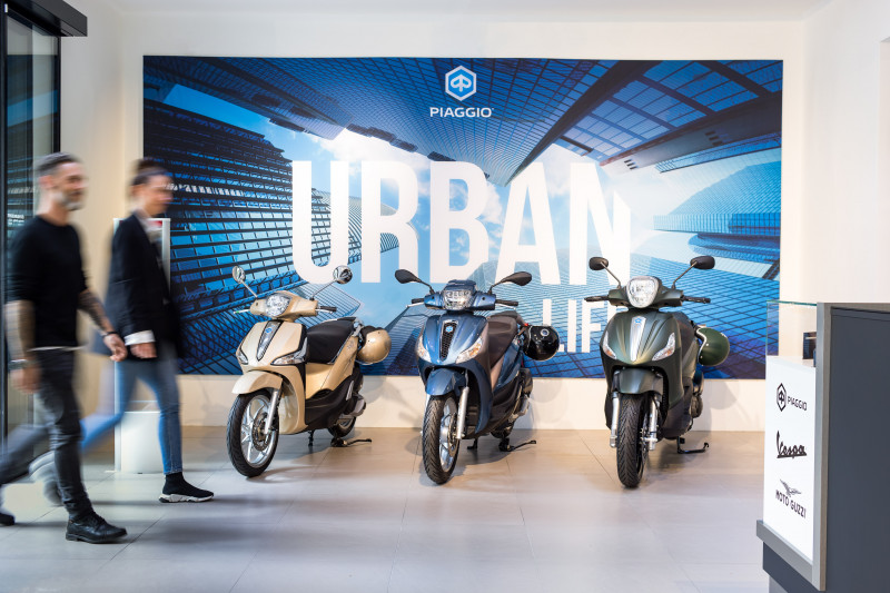 Piaggio vehicles in the Faber showroom with Piaggio Urban banner in the background